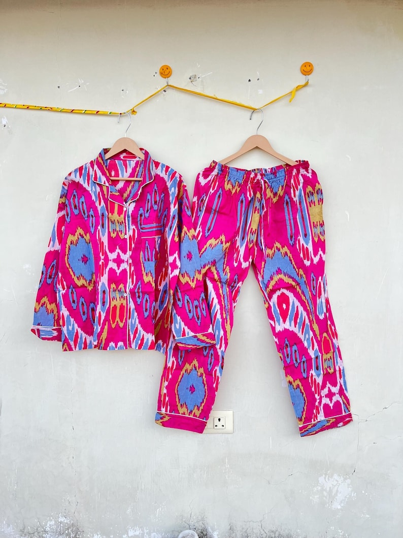 May include: A pink and blue patterned pajama set with a long-sleeved shirt and pants. The shirt has a button-up front and the pants have an elastic waistband.