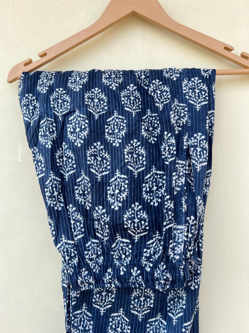 K&ouml;nnte beinhalten: Eine blaue Baumwollhose mit wei&szlig;em Blumenmuster. Die Hose hat einen elastischen Bund und eine lockere Passform.