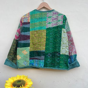 Puede incluir: Una chaqueta acolchada verde con un dise&ntilde;o de patchwork. La chaqueta tiene un cuello redondo y mangas largas. La tela es una mezcla de diferentes patrones y colores, incluyendo verde, azul y rosa.