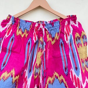 May include: Pink, blue, and yellow patterned pants with a drawstring waist.