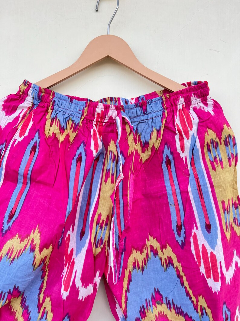 May include: Pink, blue, and yellow patterned pants with a drawstring waist.