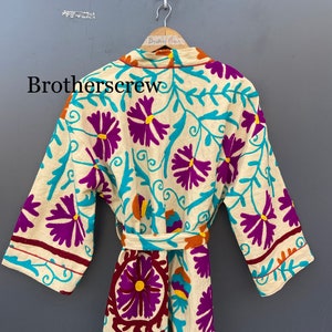 May include: A white robe with a floral pattern in shades of purple, turquoise, and orange. The robe has a tie belt and long sleeves.