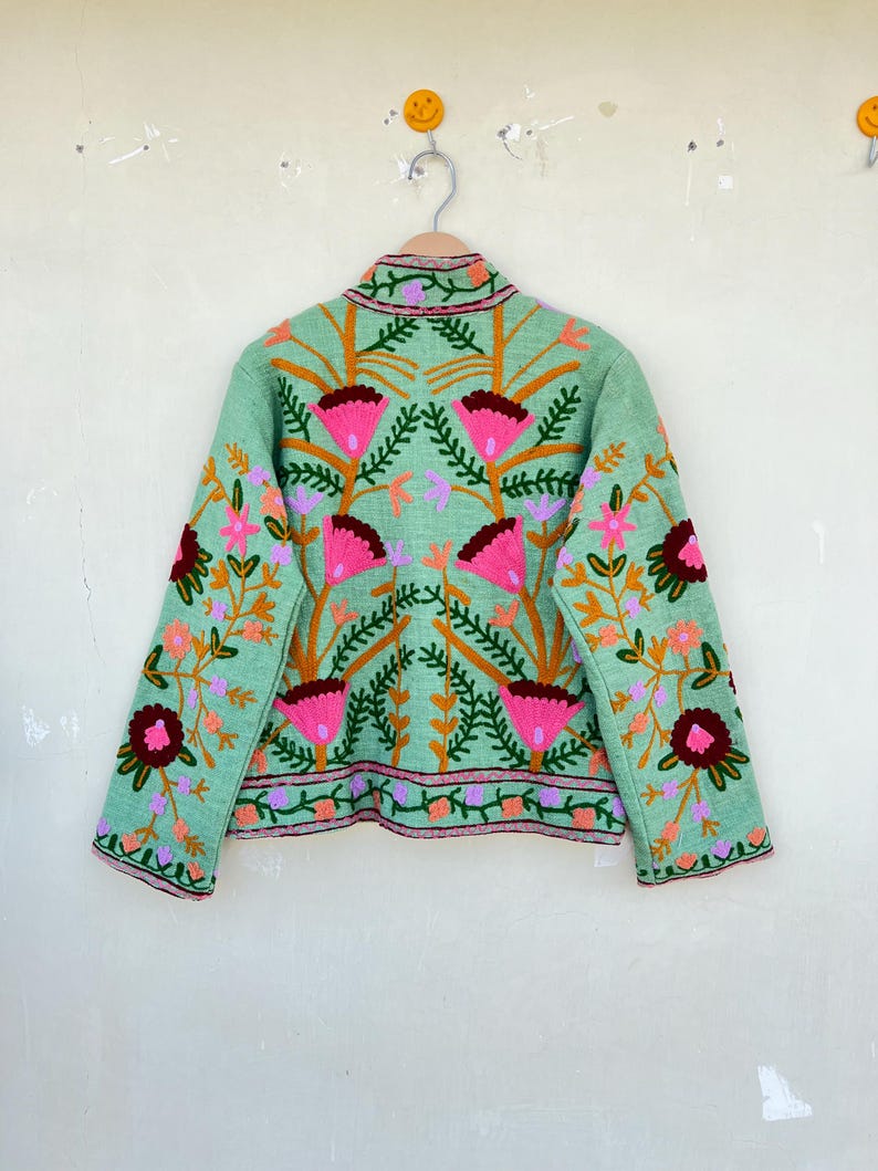 May include: A mint green jacket with a floral embroidery design. The embroidery features pink, orange, and burgundy flowers with green leaves.