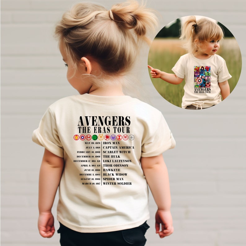 May include: A beige t-shirt with a black graphic of the Avengers logo and a list of the Avengers characters and their first appearances. The text reads "Avengers The Eras Tour".