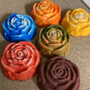 May include: Six handmade soap bars shaped like roses in various colors, including blue, orange, yellow, green, red, and brown.