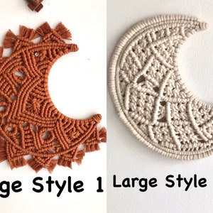 May include: Two large macrame wall hangings in the shape of a crescent moon. The moon on the left is a burnt orange color and the moon on the right is a natural white color. Both moons have a detailed knot pattern and fringe around the edges. The text "Large Style 1" is below the orange moon and "Large Style 2" is below the white moon.