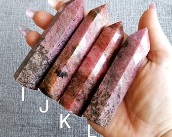 Puede incluir: Cinco puntas de piedras preciosas pulidas de color rosa y gris, también conocidas como rodonita, están dispuestas en fila. Las puntas son todas de aproximadamente el mismo tamaño y forma, y tienen un acabado liso y pulido. Las puntas están dispuestas en fila, con la punta más grande en la parte superior y la punta más pequeña en la parte inferior. Las puntas están todas enfocadas y el fondo está desenfocado.