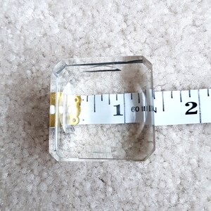 Puede incluir: Un porta anillos cuadrado de vidrio transparente que mide 1 pulgada de ancho.