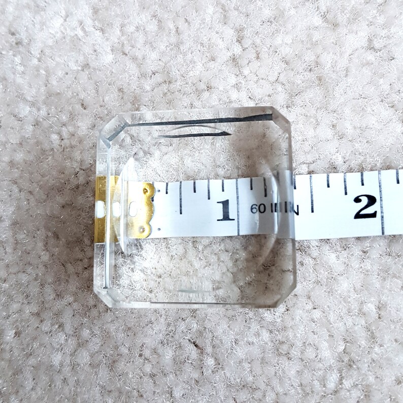Puede incluir: Un porta anillos cuadrado de vidrio transparente que mide 1 pulgada de ancho.