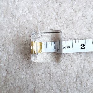 Puede incluir: Un cubo de vidrio transparente con una cinta m&eacute;trica encima. La cinta m&eacute;trica indica "60 IN" y tiene marcas para pulgadas.