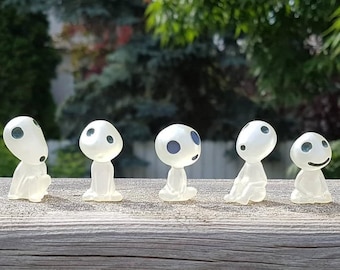 Puede incluir: Seis figuritas blancas translúcidas con ojos azules. Las figuritas están en fila sobre una superficie de madera. Todas están en diferentes poses, algunas están sentadas, otras de pie y otras mirando hacia arriba.