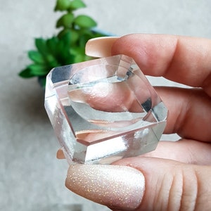 Puede incluir: Un porta anillos de cristal transparente con una base cuadrada y una abertura redonda en el centro. El porta anillos est&aacute; hecho de vidrio transparente y tiene un acabado liso y pulido.
