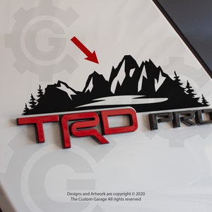 May include: Black and red "TRD PRO" emblem with a black mountain range decal above it. The decal features a lake and pine trees.