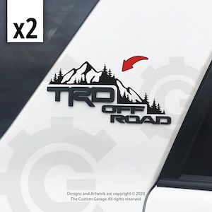 May include: Black and white decal with the words "TRO OFF ROAD" and a mountain range graphic. The decal is mounted on a white car door.