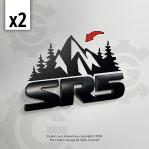May include: Black metal emblem with the text "SR5" and a mountain silhouette with pine trees. The mountain silhouette has a red arrow pointing to the top of the mountain.