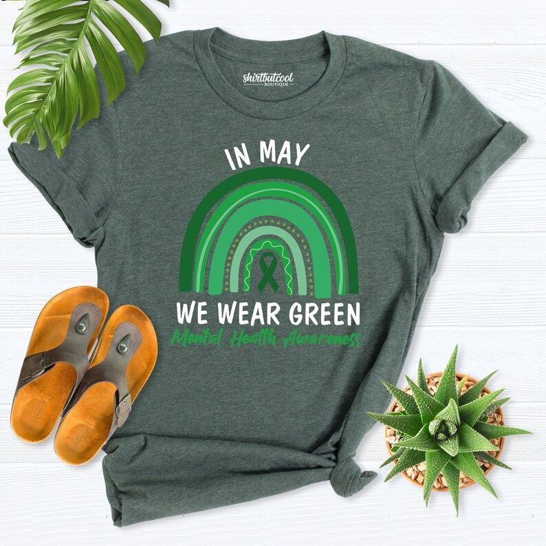 K&ouml;nnte beinhalten: Gr&uuml;nes T-Shirt mit einem Regenbogen-Design und dem Text "Im Mai tragen wir Gr&uuml;n f&uuml;r die psychische Gesundheit".