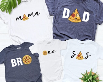 May include: A collection of four shirts and one bodysuit featuring pizza-themed graphics. The white shirts display the text mama, one, and sis with pizza slices. The dark blue shirts feature the text dad and bro with pizza graphics.