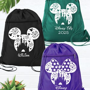 May include: Three drawstring bags with different designs. The first bag is black with a white Mickey Mouse head silhouette with fireworks and a castle inside. The second bag is green with a white Mickey Mouse head silhouette with fireworks and a castle inside. The third bag is purple with a white Minnie Mouse bow silhouette with fireworks and a castle inside. The bags have the text "Disney Trip 2025", "William", and "Disney" on them.
