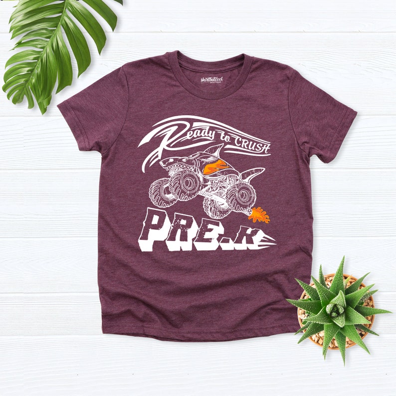 May include: A maroon t-shirt with a white graphic of a monster truck with flames and the text "Ready to Crush Pre-K".