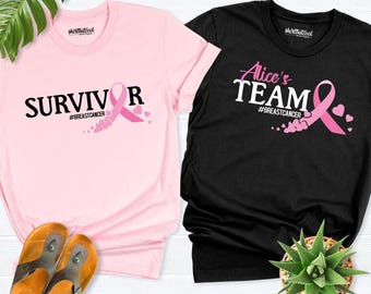 May include: A light pink t-shirt with the black text SURVIVOR and a black t-shirt with the white and pink text Alice's TEAM, both featuring a pink breast cancer awareness ribbon graphic and the hashtag #BREASTCANCER printed on the front.
