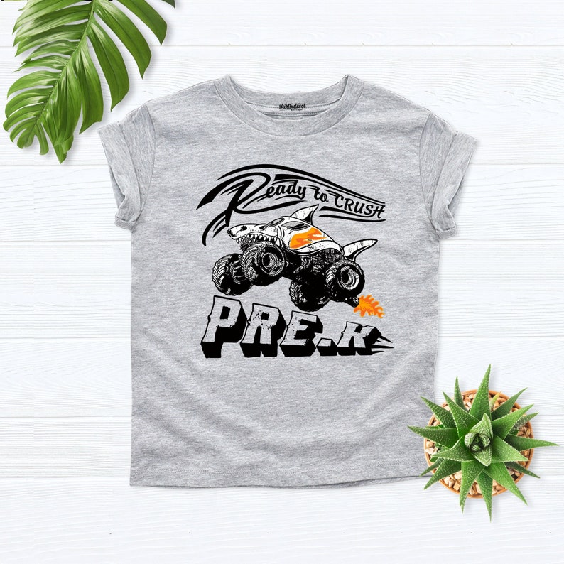 May include: Gray short-sleeved t-shirt with a black and white graphic of a monster truck with the text "Ready to Crush Pre-K".