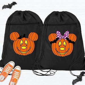 May include: Two black drawstring bags with orange pumpkin faces, Mickey Mouse ears, and smiling faces. One has a black bat, the other a purple polka dot bow. Orange sneakers are at the bottom.