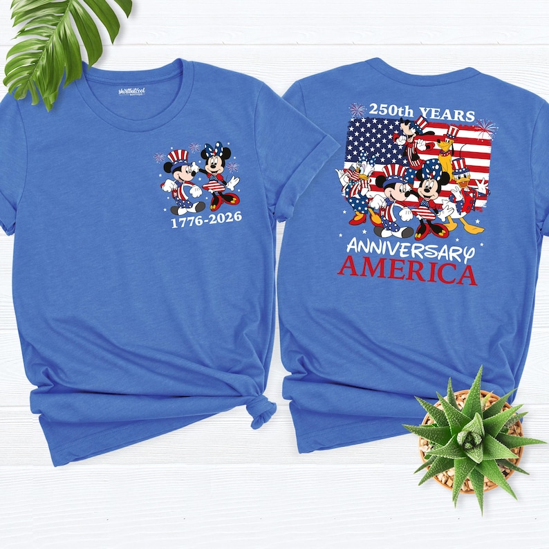 May include: Two blue t-shirts featuring Mickey and Minnie Mouse in patriotic attire. The front of the shirt displays the characters with the text "1776-2026". The back of the shirt has a design with the American flag and the words "250th YEARS ANNIVERSARY AMERICA".