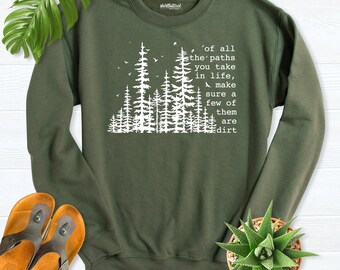 May include: An olive green crewneck sweatshirt featuring a white graphic of pine trees and the text: Of all the paths you take in life, make sure a few of them are dirt. The long-sleeved pullover has a ribbed collar, cuffs, and hem.