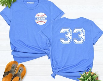 May include: A light blue short-sleeve t-shirt featuring a small baseball graphic with the text BOMBERS on the front left chest and a large white number 33 with a baseball stitch texture printed on the back of the garment.