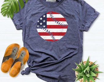 May include: A heather navy blue short-sleeve t-shirt featuring a distressed graphic of a baseball with an American flag pattern. The shirt has a crew neckline and the text shirtbutcool boutique printed on the inside collar area.