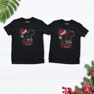 Peut inclure: Deux t-shirts noirs avec un motif de No&euml;l repr&eacute;sentant les oreilles de Mickey Mouse avec un bonnet de P&egrave;re No&euml;l et le texte "Disney Christmas 2024".