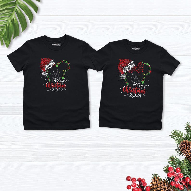 Peut inclure: Deux t-shirts noirs avec un motif de No&euml;l repr&eacute;sentant les oreilles de Mickey Mouse avec un bonnet de P&egrave;re No&euml;l et le texte "Disney Christmas 2024".