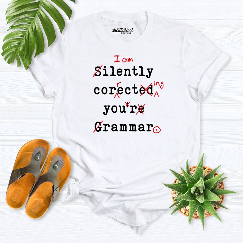 Puede incluir: Camiseta blanca con el texto "I am silently corrected you're Grammar" tachado en rojo y un c&iacute;rculo rojo.