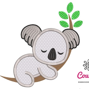 Puede incluir: Diseño bordado de un koala gris durmiendo en una rama marrón con hojas verdes. El koala tiene un patrón de puntos blancos y ojos negros. El diseño es de CouCou Embroidery Designs.