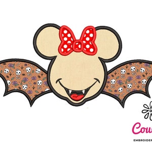 Pode incluir: Um morcego de desenho animado com um sorriso malicioso usa um laço vermelho com bolinhas brancas. As asas do morcego são marrons com um padrão de caveiras e ossos cruzados.