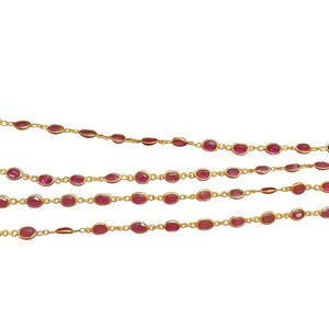 Könnte beinhalten: Eine zarte goldene Halskette mit ovalen, rubinroten Edelsteinen. Die Edelsteine sind gleichmäßig entlang der Goldkette angeordnet und bilden ein durchgehendes, elegantes Design. Die Halskette hat einen Verschluss.