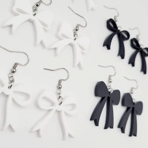 May include: A pair of black and white bow earrings. The earrings are made of acrylic and have a simple, elegant design.