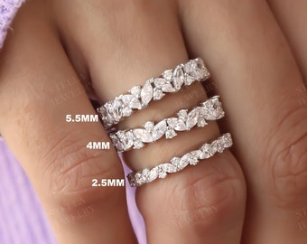 May include: Three diamond eternity rings of varying widths are displayed on a finger. The rings are labeled 5.5mm, 4mm, and 2.5mm. The rings feature a floral design with small, round diamonds and larger marquise-cut diamonds.