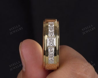 May include: A gold band with a square-shaped diamond in the center and smaller diamonds on the sides. The band is set with a row of smaller diamonds on each side of the center stone.
