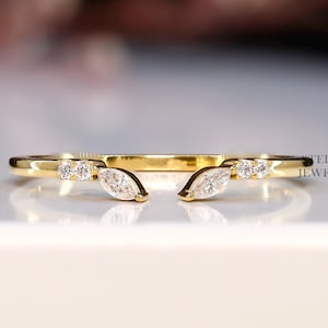 Könnte beinhalten: Ein goldfarbener Ring mit einem einzigartigen Design. Der Ring hat kleine, runde und marquiseförmige Edelsteine. Der Ring trägt den Text "STELLA JEWELRY" an der Seite. Der Ring liegt auf einer weißen Oberfläche.