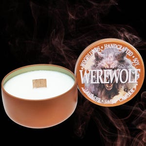 May include: A brown candle tin with a white candle and a wooden wick. The tin lid features a werewolf illustration with the word "WEREWOLF" and the scent notes "Lavender, Sage, Camphor". The candle is handcrafted with soy wax.