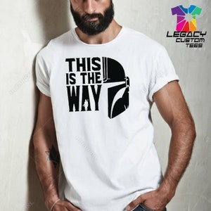Puede incluir: Camiseta blanca con un gr&aacute;fico negro de un casco mandaloriano y el texto "This is the Way".