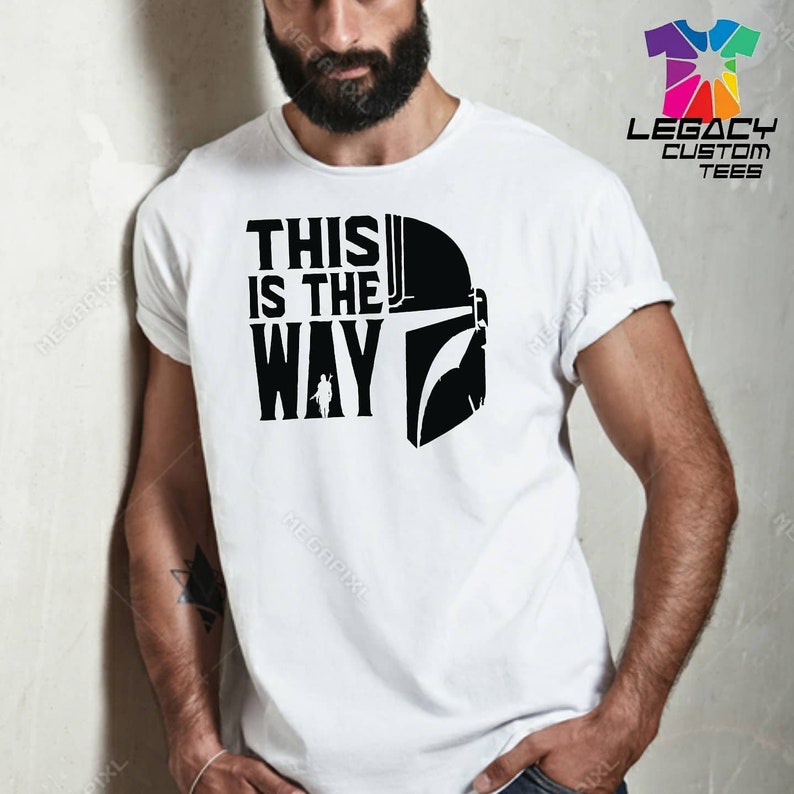 Puede incluir: Camiseta blanca con un gr&aacute;fico negro de un casco mandaloriano y el texto "This is the Way".