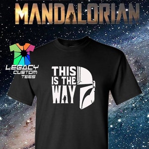 Puede incluir: Camiseta negra con texto blanco que dice "This is the Way" y un gr&aacute;fico de casco mandaloriano.