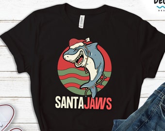 May include: Black t-shirt with a graphic of a shark wearing a Santa hat and holding Christmas lights. The text "SANTAJAWS" is below the shark.