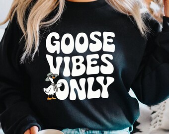 May include: Black sweatshirt with white text that reads "Goose Vibes Only". A cartoon goose wearing a hat is to the left of the text.