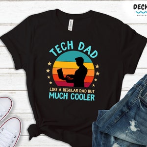 May include: Black t-shirt featuring a retro-style graphic of a person using a laptop. The graphic says "Tech Dad" and "Like a regular dad but much cooler".