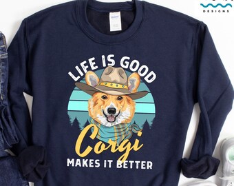 Könnte beinhalten: Ein marineblaues Sweatshirt mit einem Aufdruck eines Corgis, der einen Cowboyhut trägt. Der Text "Life is good Corgi makes it better" ist auf dem Sweatshirt aufgedruckt.