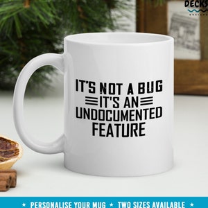 May include: White ceramic mug with a black graphic that reads "It's not a bug, it's an undocumented feature".