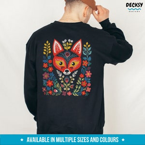 K&ouml;nnte beinhalten: Schwarzes Sweatshirt mit einem bunten Fuchs-Design auf der R&uuml;ckseite. Der Fuchs ist von Blumen und Bl&auml;ttern umgeben. Das Design ist im Stil der Volkskunst.